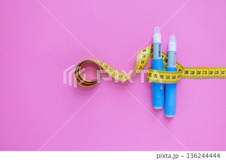 Concept image of diabetes and obesity treatment with two insulin pens and a measuring tape on pastel background. drugs injection ozempic for weight loss 136244444