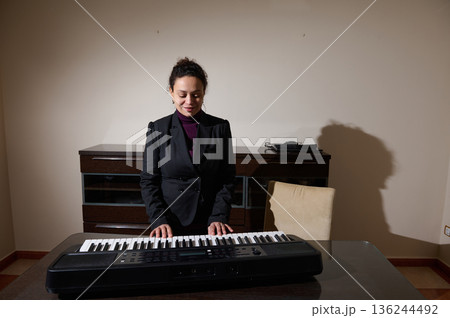 Businesswoman Plays Keyboard At Desk In Modern Home Office Studio Setting For Creative Music Businesswoman Plays Keyboard At Desk In Modern Home Office Studio Setting For Creative Music 136244492