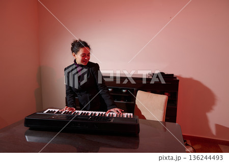 Professional Woman In Blazer Plays Keyboard In Modern Office With Warm Pink Lighting 136244493