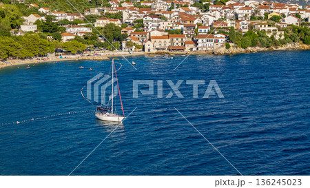 White sailboat on calm Adriatic waters near coastal town in Croatia summer scene aerial view 136245023