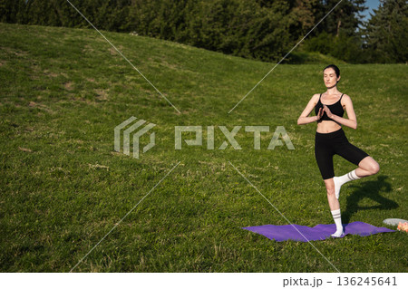 Practicing yoga in a sunny green park during a tranquil afternoon 136245641