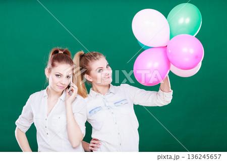 Two girls with mobile phone and balloons 136245657