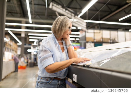 Middle-aged woman shopping for art supplies in a well-lit store during the day 136245796