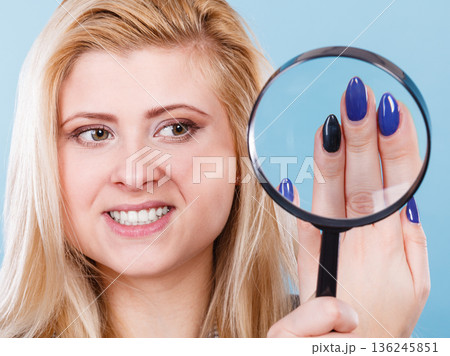 Woman looking at nails through magnifying glass 136245851