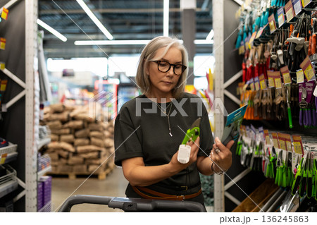 Woman shopping for gardening tools in a home improvement store during the afternoon 136245863