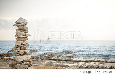 A stone pyramid of flat stones on a rocky seashore. 136246056