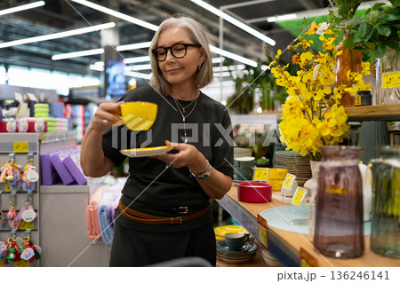 Woman shopping for dinnerware at home goods store in bright, organized atmosphere during the day Woman shopping for dinnerware at home goods store in bright, organized atmosphere during the day 136246141