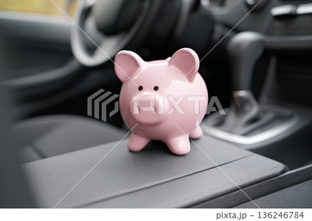 A pink piggy bank is placed on the center console inside a car. This shows the connection between saving money and daily life. It highlights the importance of planning finances. A pink piggy bank is placed on the center console inside a car. This shows the connection between saving money and daily life. It highlights the importance of planning finances. 136246784