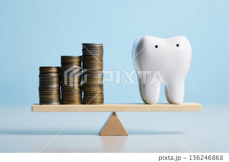 Two stacks of coins are placed on one side of a scale, while a white tooth model sits on the other side, representing the balance between oral health and financial planning. 136246868