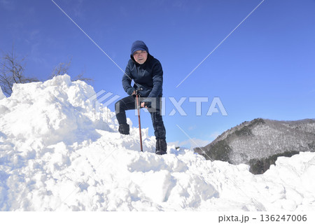 雪の階段を杖を使って上がり降りでリハビリをしている老人 雪の階段を杖を使って上がり降りでリハビリをしている老人 136247006