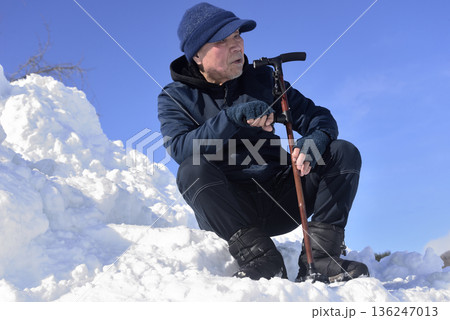 雪の階段を杖を使って上がり降りでリハビリをしている老人 136247013