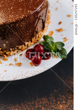 Chocolate glazed cake with cherries and mint on white plate, close up 136247265