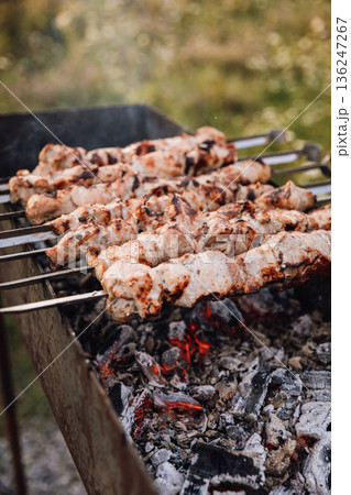 Pork shashlik on skewers grilling over hot charcoal outdoors, close up 136247267