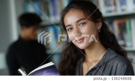 Young woman holding book in library Young woman holding book in library 136248688