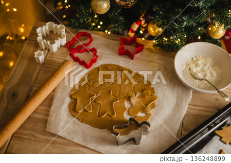 Holiday background. Uncooked raw Christmas gingerbread cookies with cookie cutters on a table, top view, flat lay Holiday background. Uncooked raw Christmas gingerbread cookies with cookie cutters on a table, top view, flat lay 136248899