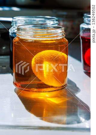 Egg soaking in yellow food dye in glass jar on sunlit kitchen table Egg soaking in yellow food dye in glass jar on sunlit kitchen table 136249502