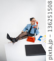 Young angry white woman in office attire working talking on vintage red phone, isolated on white background. In a blue shirt with a tie. Business occupation. Boss . 136251508