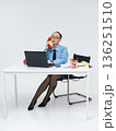 Young white woman in office attire working on laptop while talking on vintage red phone, isolated on white background 136251510