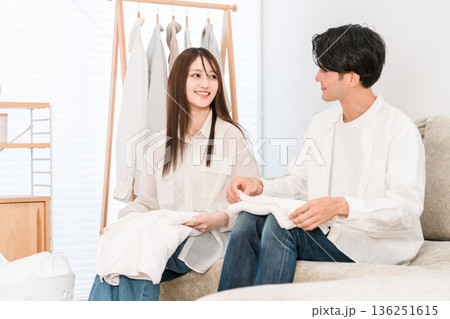 リビングで洗濯物を畳む笑顔の夫婦,カップル(家事参加,家事分担) リビングで洗濯物を畳む笑顔の夫婦,カップル(家事参加,家事分担) 136251615