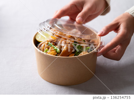 Close up of hands closing an eco-friendly paper bowl of Thai food (Pad See Ew) 136254755
