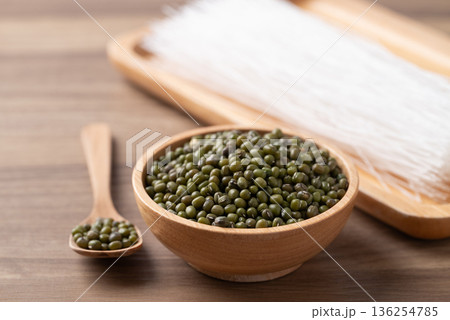 Mung beans seeds and dried glass noodles on a wooden table, raw ingredients for Thai vermicelli Mung beans seeds and dried glass noodles on a wooden table, raw ingredients for Thai vermicelli 136254785
