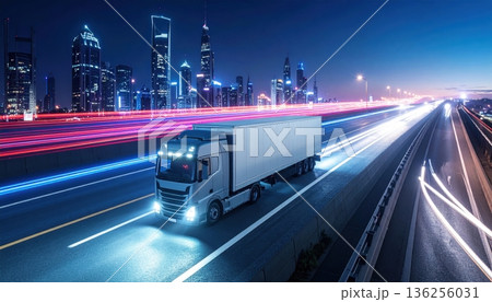 Fast cars drive with blurred motion along the dark urban highway at night, creating a cityscape of light and speed on the busy transport motorway 136256031