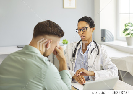 Female doctor counseling stressed male patient during appointment at modern clinic 136258785