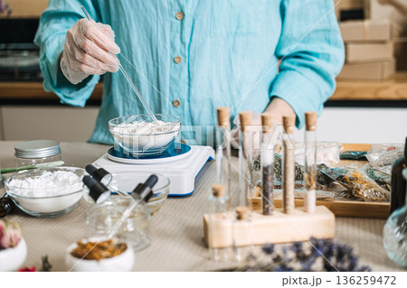 Hands in gloves use glass rod to stir powder base in bowl on scale. Fresh mixing, powder base, liquid activator, zero preservative. Hands in gloves use glass rod to stir powder base in bowl on scale. Fresh mixing, powder base, liquid activator, zero preservative. 136259472