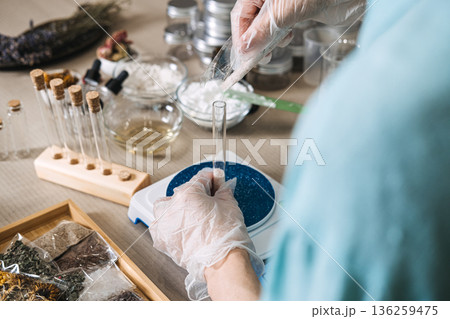 Hands in gloves pour powder from plastic bag into glass test tube on digital scale in apothecary workshop. active dry powder, zero-preservative DIY, anhydrous shelf-life, pure botanical mix. Hands in gloves pour powder from plastic bag into glass test tube on digital scale in apothecary workshop. active dry powder, zero-preservative DIY, anhydrous shelf-life, pure botanical mix. 136259475