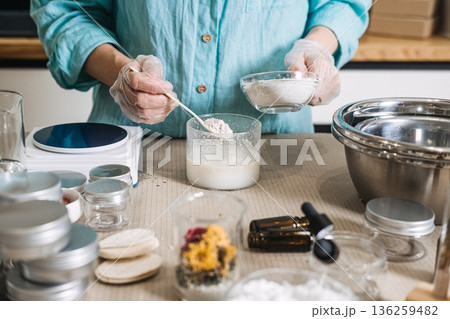 Person wearing gloves adds powder to liquid mixture during artisanal skincare formulation. plastic-free beauty making, sustainable cosmetic lab, eco-conscious diy, bulk ingredient aesthetic. Person wearing gloves adds powder to liquid mixture during artisanal skincare formulation. plastic-free beauty making, sustainable cosmetic lab, eco-conscious diy, bulk ingredient aesthetic. 136259482