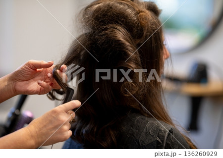 Rear view stylist teasing hair volume, hands backlighting frizz and texture visible, fingers shaping sections, finishing product pending, focused salon prep mood Rear view stylist teasing hair volume, hands backlighting frizz and texture visible, fingers shaping sections, finishing product pending, focused salon prep mood 136260929