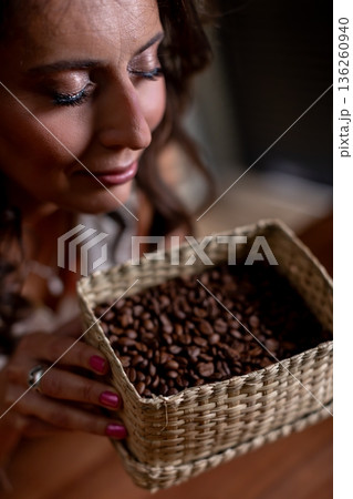 Calm smiling woman, Peaceful lady holding beans gently, Relaxed woman with basket and soft expression, Serene female figure with beans beneath gentle shadow lighting 136260940