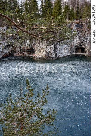 Winter view of Ruskeala Mountain Park marble canyon lake with icy water and grottoes. Natural landscape for travel tourism. 136261005