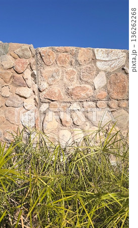 Serene Rural Landscape With Stones. Sunlit Rustic Wall Surrounded By Lush Grasses. Bright Rural Setting Featuring Ancient Stones And Wild Grasses Under Clear Blue Sky Serene Rural Landscape With Stones. Sunlit Rustic Wall Surrounded By Lush Grasses. Bright Rural Setting Featuring Ancient Stones And Wild Grasses Under Clear Blue Sky 136262268