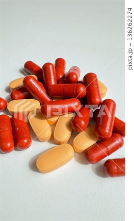 Colorful Capsules Stacked Vertically. Bright Capsules Arranged In Vertical Display. Dynamic Arrangement Of Red And Orange Capsules Emphasizing Energetic Brand Messaging 136262274