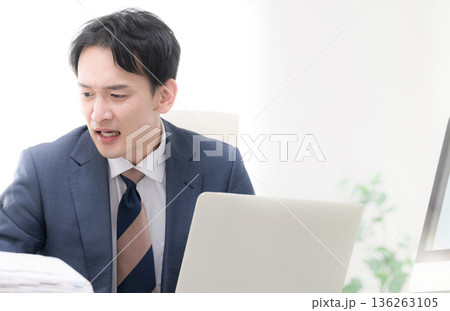 経営の戦略や結果のグラフを見る社長や経営者の悩む困る、忙しい焦る慌てるスーツを着た男性のイメージ 136263105