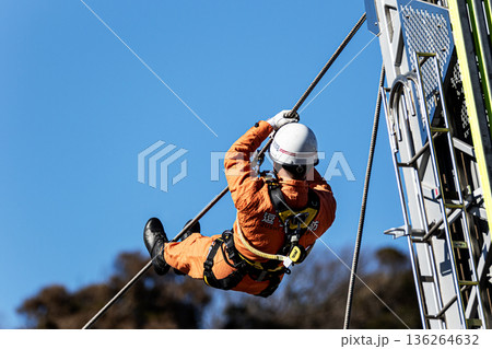 出初式ではしご付消防車の高く伸ばしたはしごからロープによる降下訓練を行うレンジャー消防隊員 136264632
