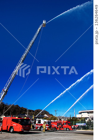 出初式で青空に向けて一斉放水訓練を実演する消防隊員 136264649