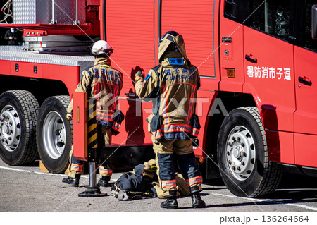 出初式で消防訓練を実演するために消防車の脇で準備をする消防隊員 136264664