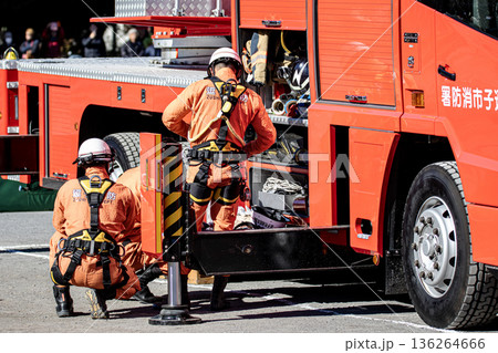 出初式で消防訓練を実演するために消防車の脇で準備をする消防隊員 136264666