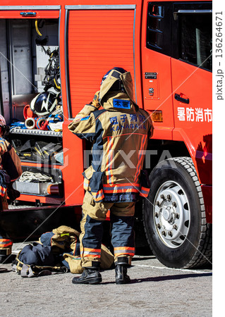 出初式で消防訓練を実演するために消防車の脇で準備をする消防隊員 136264671