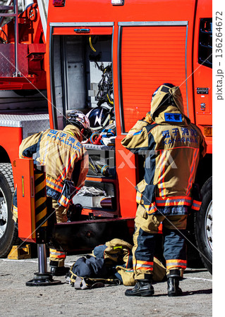 出初式で消防訓練を実演するために消防車の脇で準備をする消防隊員 136264672