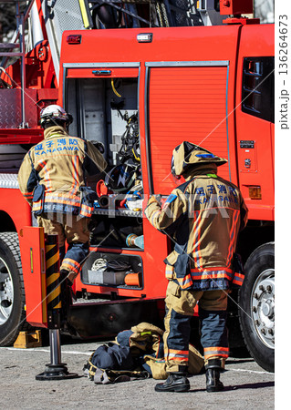 出初式で消防訓練を実演するために消防車の脇で準備をする消防隊員 136264673