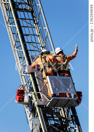 出初式ではしご付消防車のはしごを伸ばし救助活動を実演する消防隊員 136264694