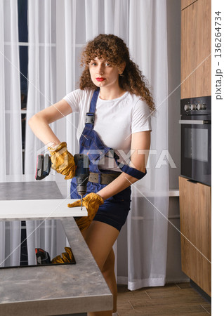 Woman using a drill in the kitchen Woman using a drill in the kitchen 136264734