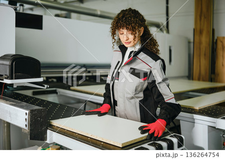 Worker operates machinery in a wood processing facility during daylight hours 136264754
