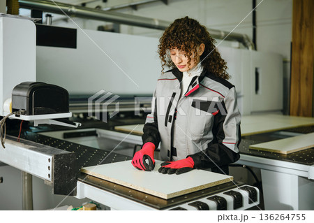 Woman sticks a label with the article on a sawn wooden sheet. 136264755