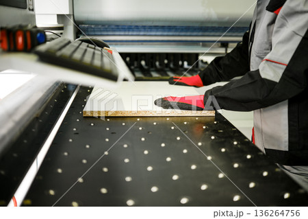 Worker uses tools to cut material in a workshop setting during the day Worker uses tools to cut material in a workshop setting during the day 136264756