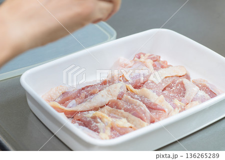 鶏もも肉に調味料を振りかける女性の手 鶏もも肉に調味料を振りかける女性の手 136265289