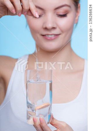 Woman holding glass with water and effervescent tablet Woman holding glass with water and effervescent tablet 136266634